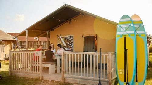Vrienden zitten op het terras van hun Glamping tent.