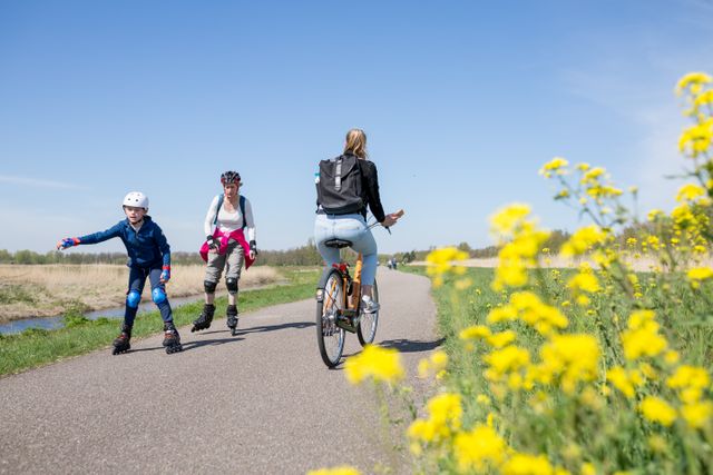Een vrouw die aan het fietsen is en twee skeelerende mensen