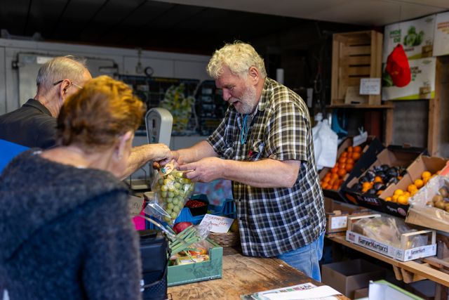 Een groente- en fruitboer die druiven aan het verkopen is.
