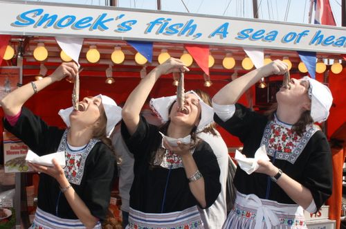 Meisjes in klederdracht eten haring.