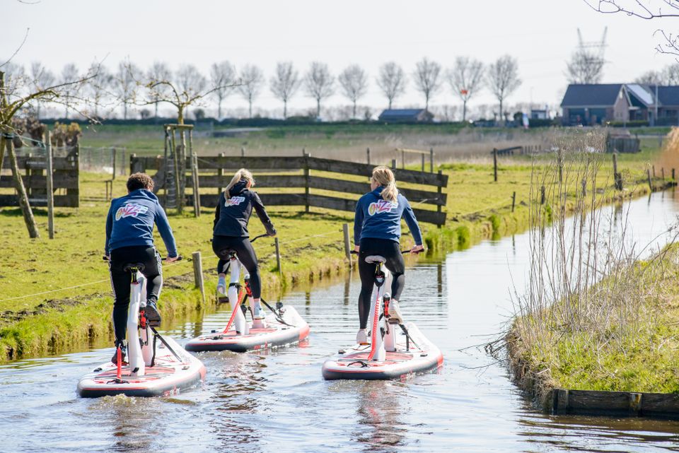 Een groepje mensen die op een fietssup van Onzzz Events door de weilanden fietsen.