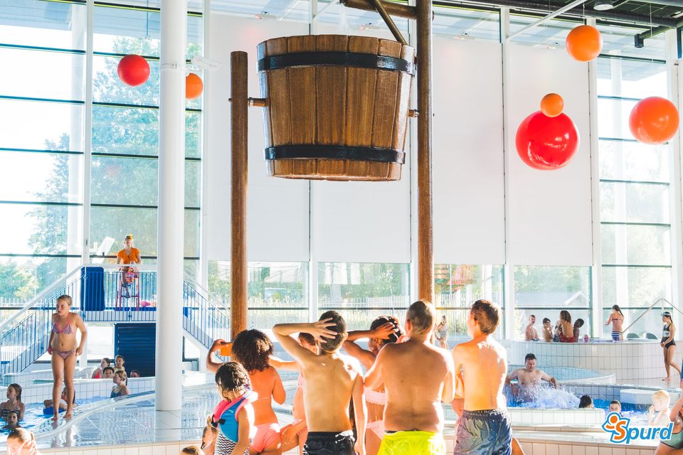 Kinderen onder een grote emmer gevuld met water in het Leeghwaterbad in Purmerend.