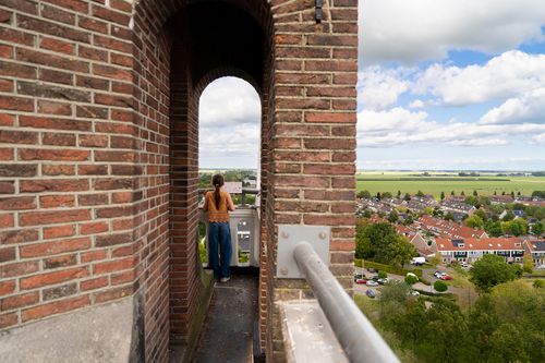Meisje op de toren van de Keyserkerk kijkend naar UNESCO Werelderfgoed Droogmakerij de Beemster.