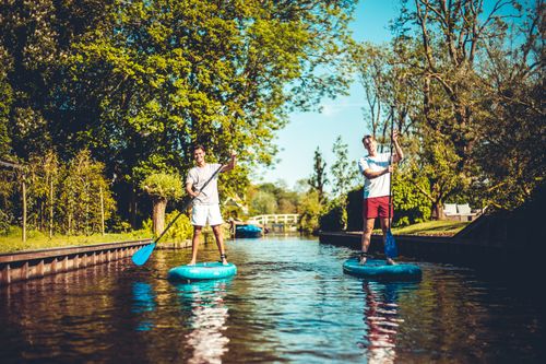 Twee jongens die op een supboard staan in Laag Holland.