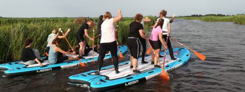 Twee groepen die op een heel groot board aan het suppen zijn