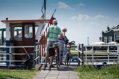 Een man en vrouw die met hun fiets een pontje opstappen