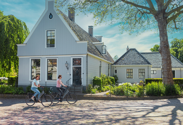 Twee vrouwen die op een zonnige dag fietsen door Broek in Waterland
