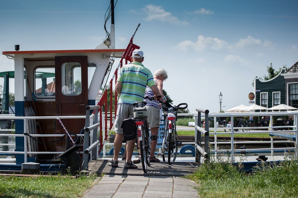 Een man en vrouw die met hun fiets een pontje opstappen