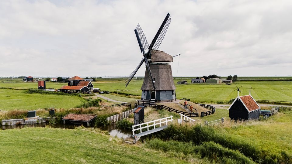De Etersheimerbraak met de molen, het bezoekerscentrum en je ziet twee mensen lopen