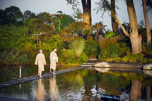 Twee mensen in badjas lopen op een pad door het water