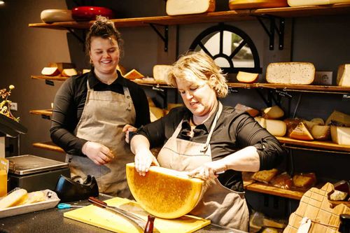 Twee vrouwen waarvan één kaas aan het schaven is.