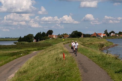 Twee fietsers die op de dijk de Aeën en Dieënroute  fietsen