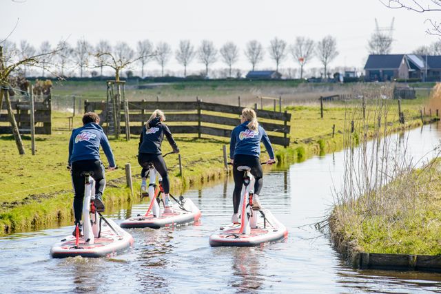 Een groepje mensen die op een fietssup van Onzzz Events door de weilanden fietsen.