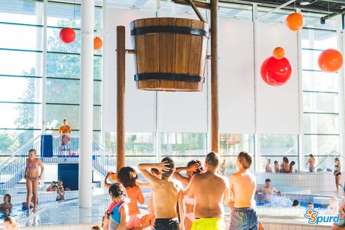 Kinderen onder een grote emmer gevuld met water in het Leeghwaterbad in Purmerend.